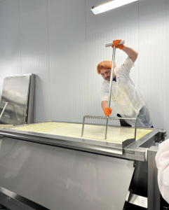 worker shaping fresh liquid cheese